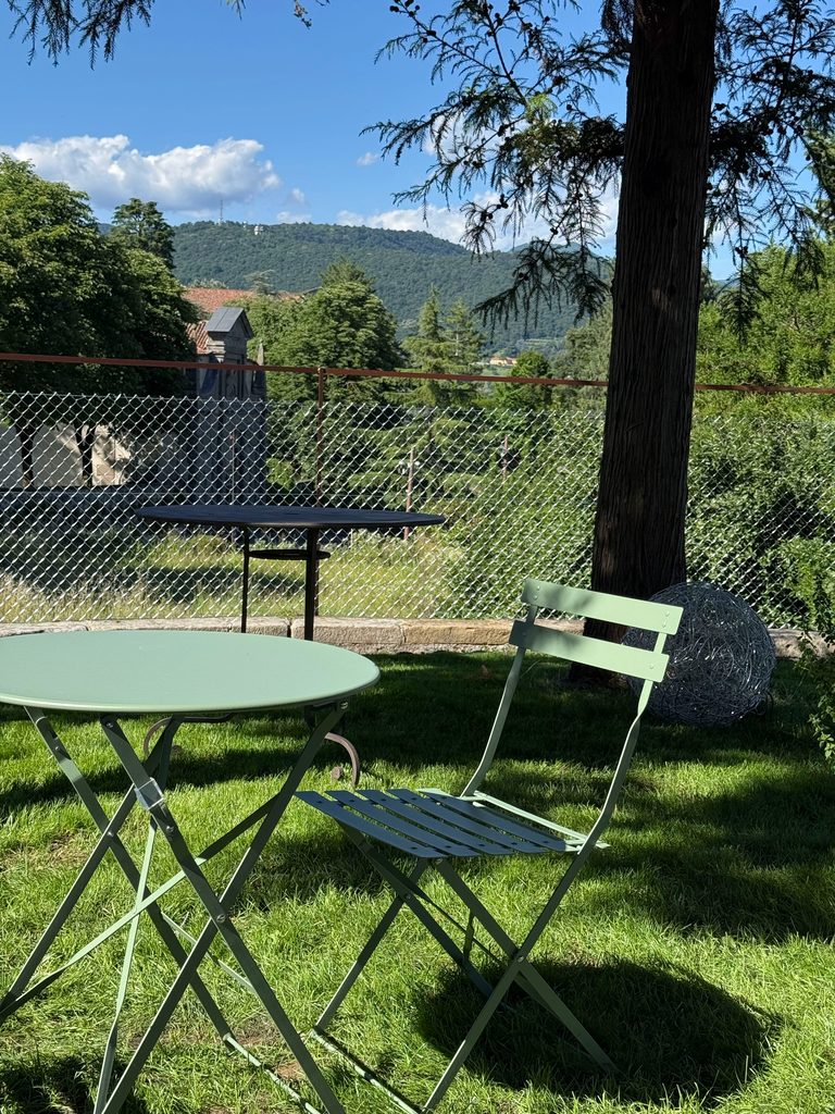 Angolo di giardino con tavolino verde salvia e vista sulle colline / Garden corner with a sage-green table and hillside view